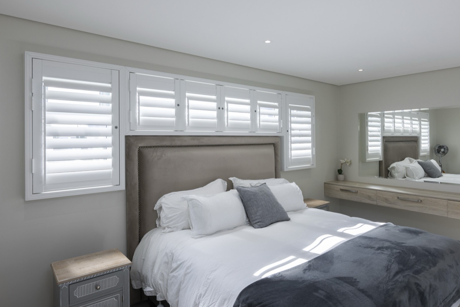 Aluminium shutters with tilted blades filtering light into a bedroom