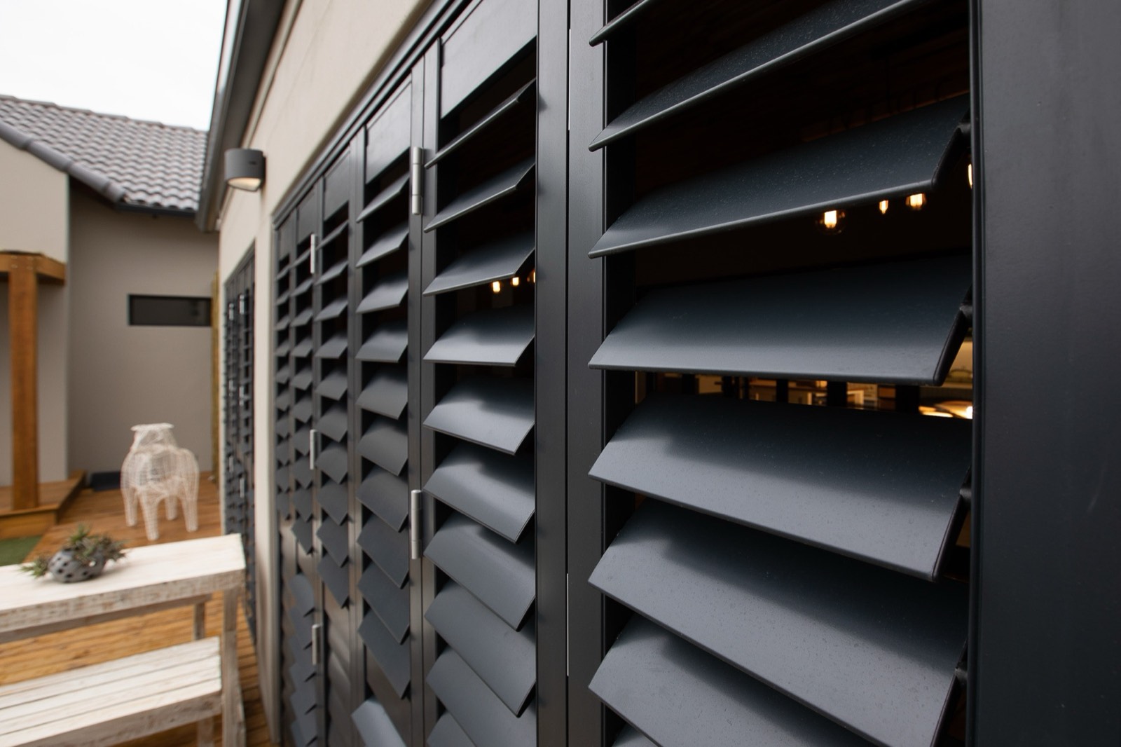 Charcoal aluminium security shutters closed across a patio on a sliding track