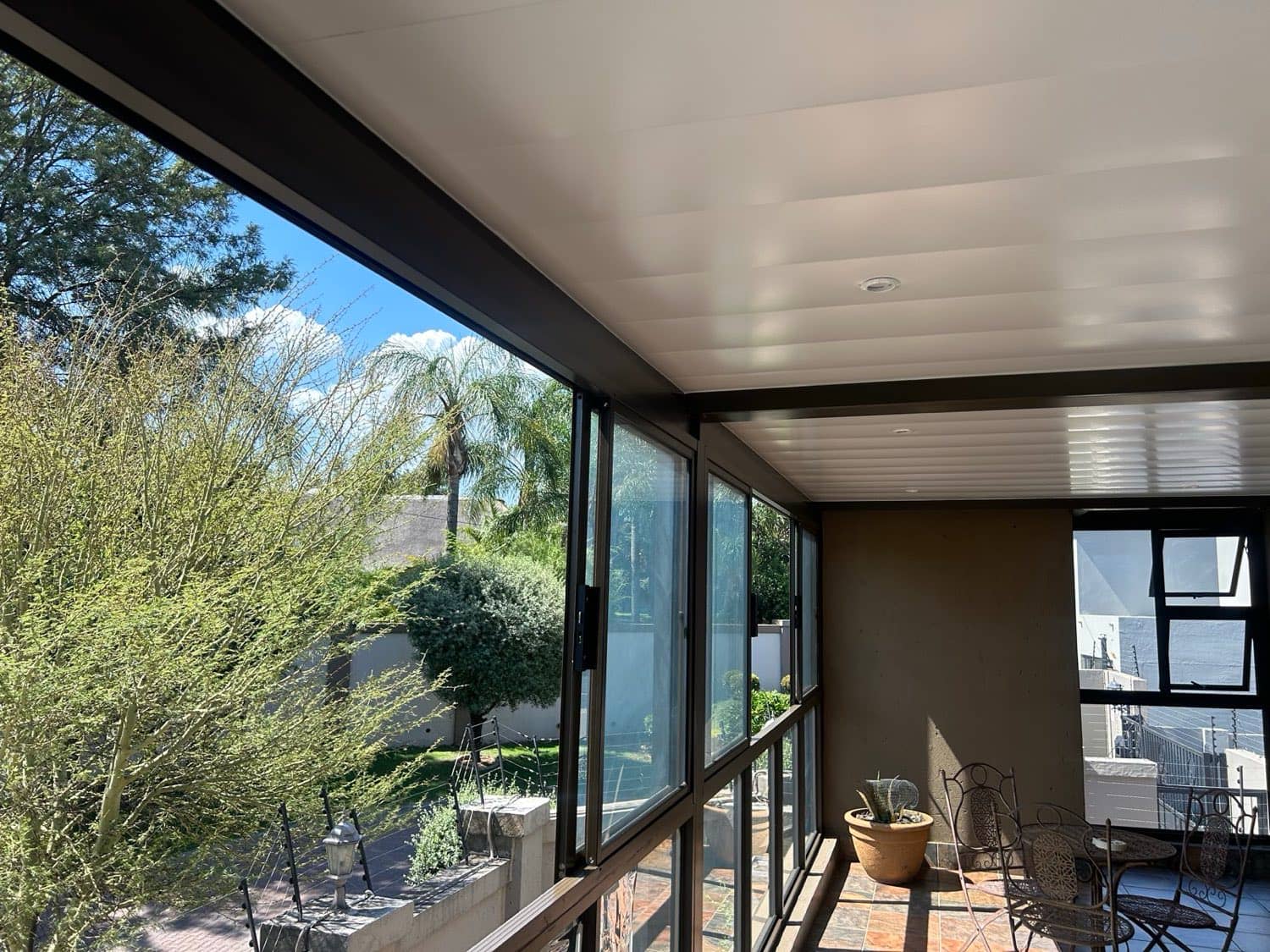 Enclosed balcony with a white panel ceiling and bronze aluminium frames in Gauteng