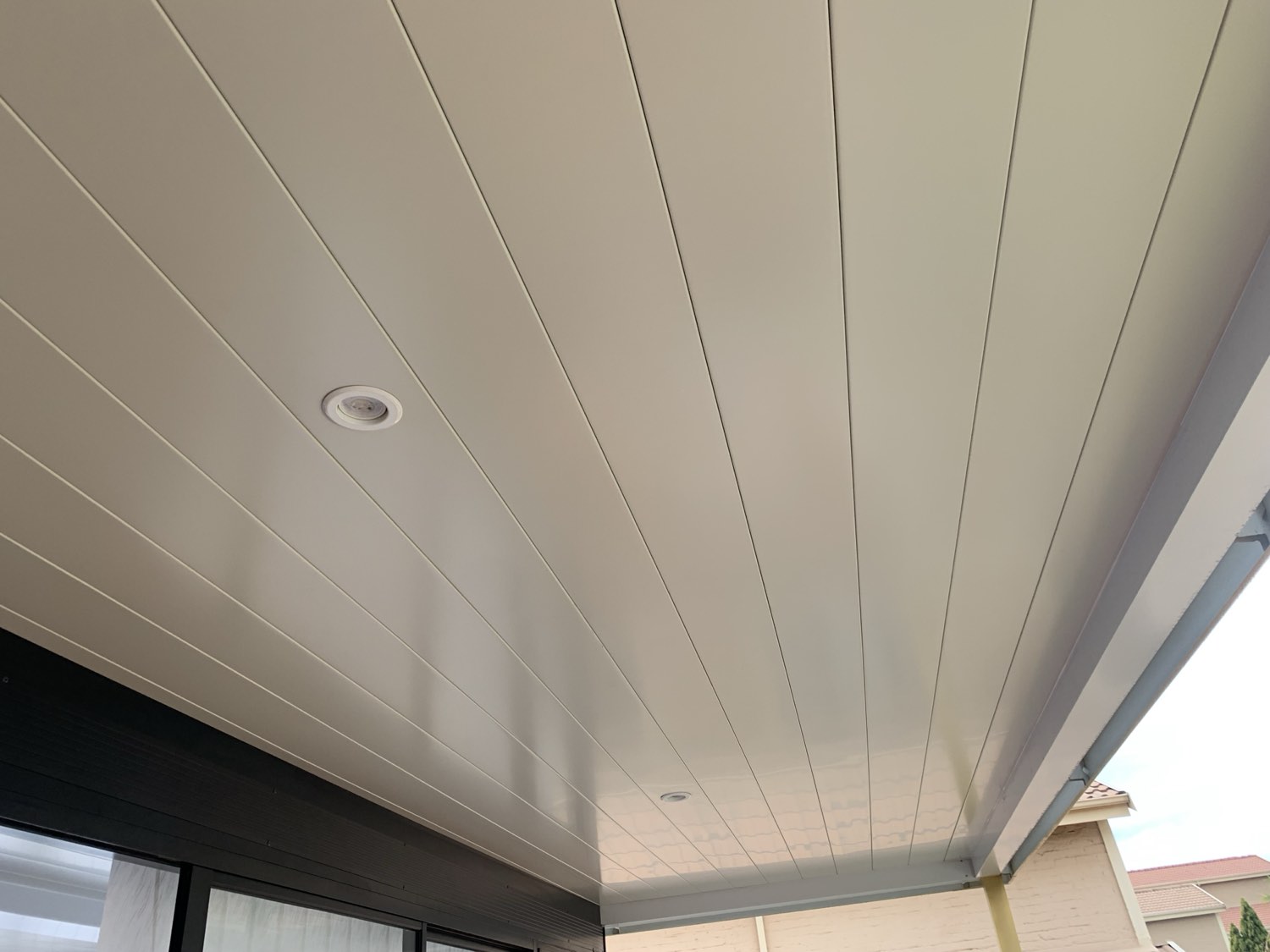 Close-up of smooth white interlocking ceiling panels with a recessed downlight