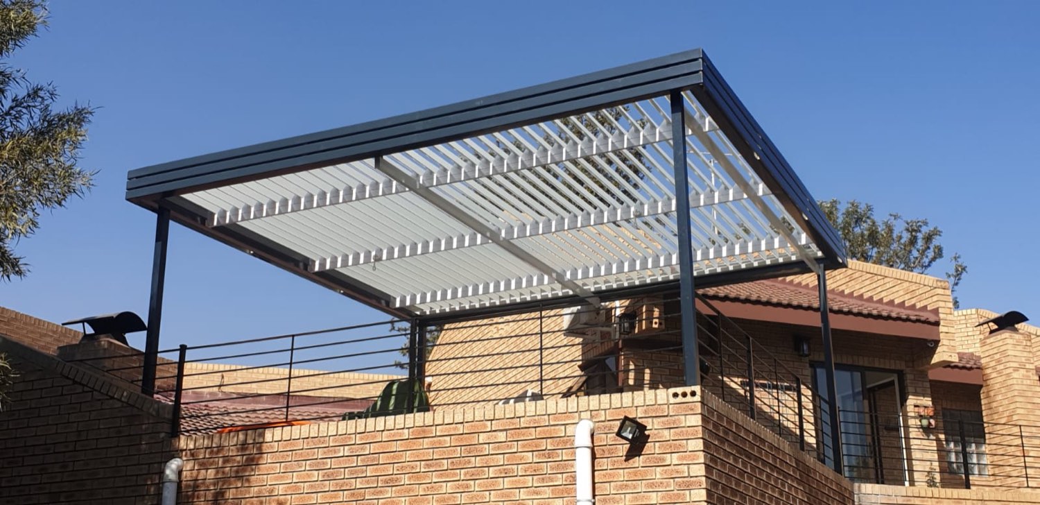 Charcoal louvre awning with white slats tilted open above a face-brick wall