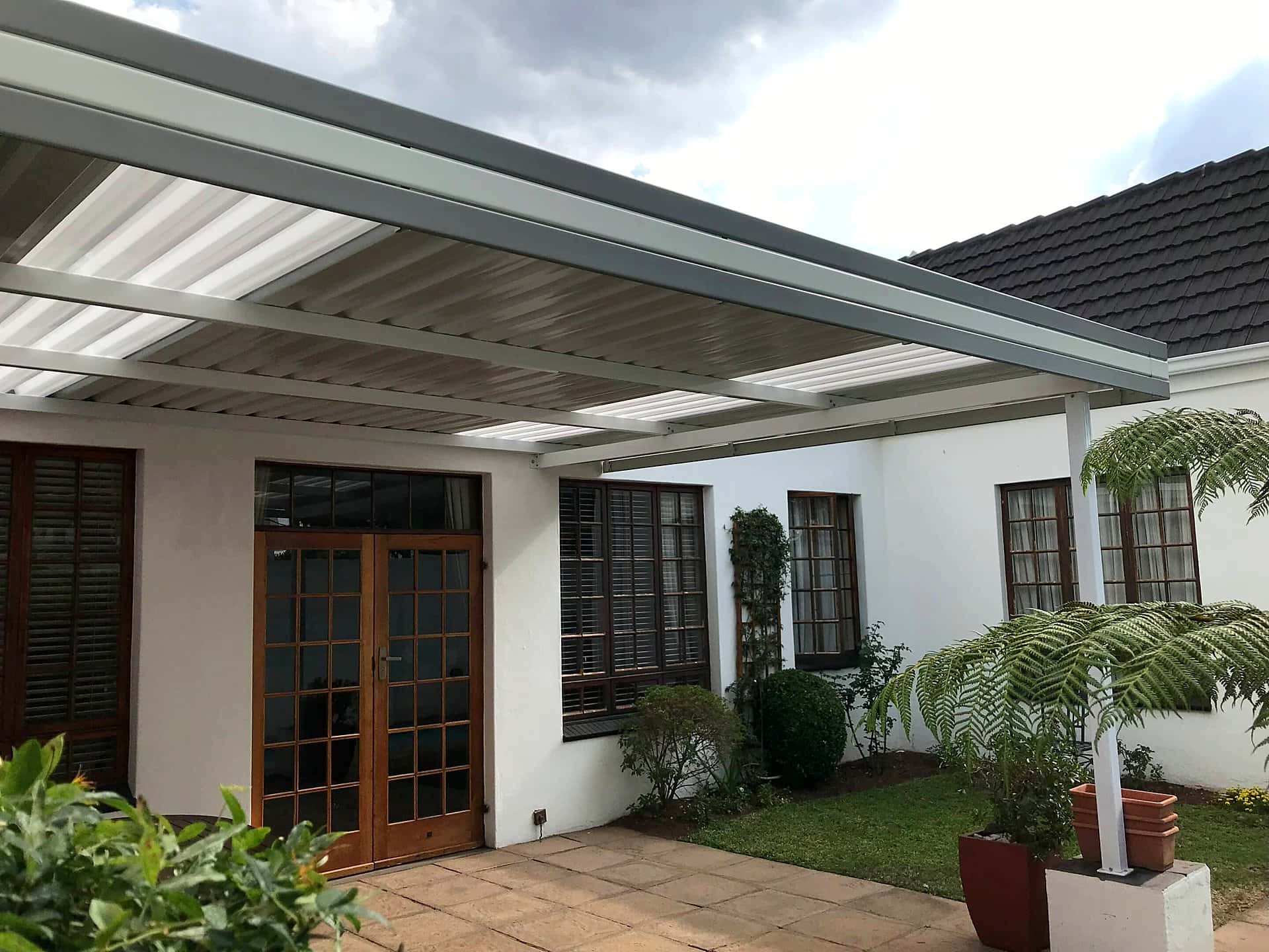 White fixed aluminium awning over a paved courtyard