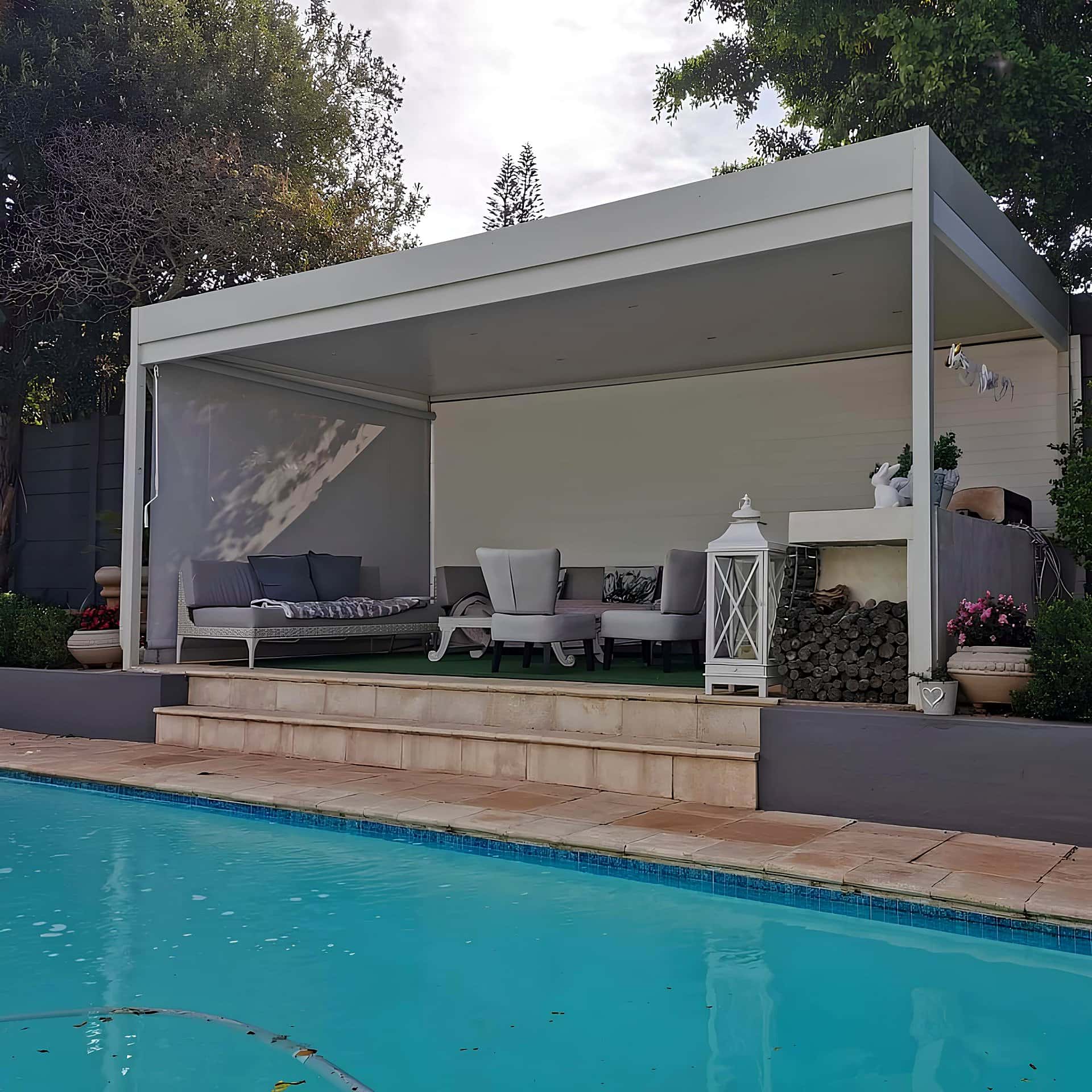 White aluminium cabana-style cover with styled furniture beside a swimming pool