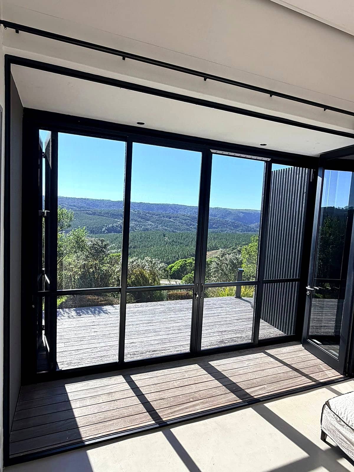 Security and insect screens on a window overlooking a Knysna forest valley