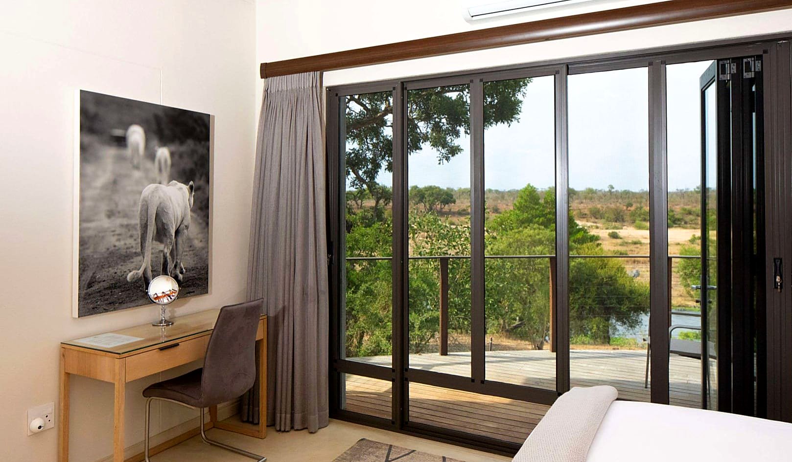 Sliding insect screens on a game lodge bedroom opening to a bushveld deck