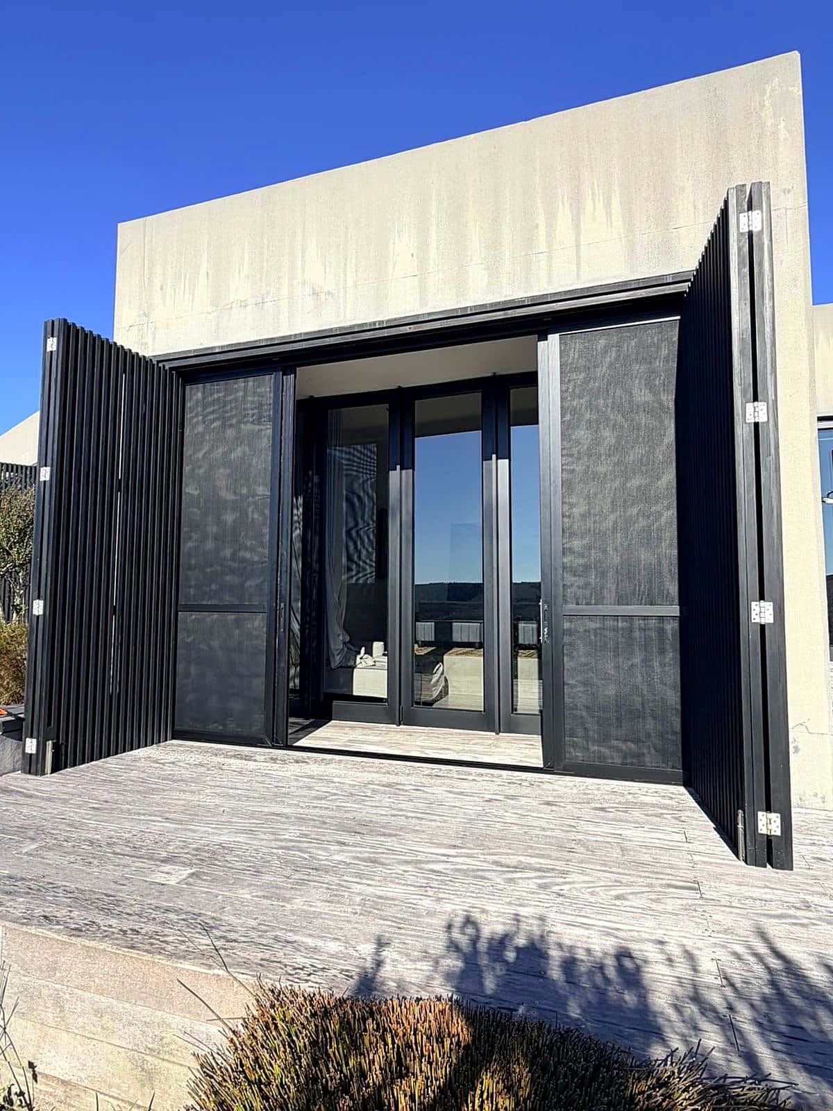 Exterior of a modern Knysna home with security screen stacks fully open