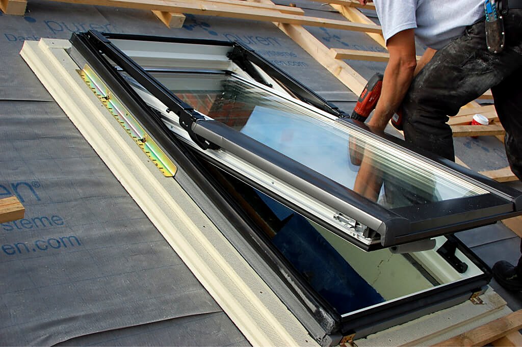Installer fitting a skylight roof window with weatherproof flashing