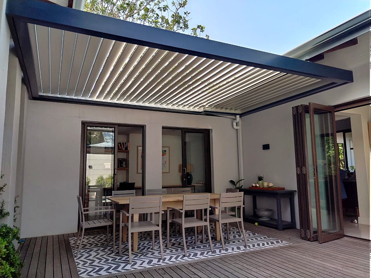Open louvre roof blades above an alfresco dining table