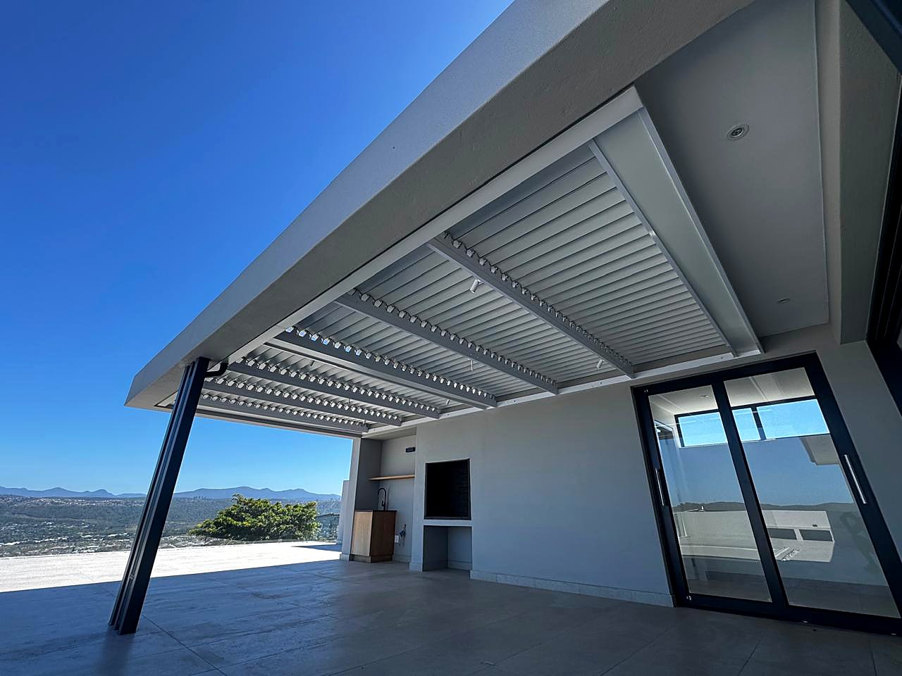 White louvre awning on a modern home with a mountain backdrop
