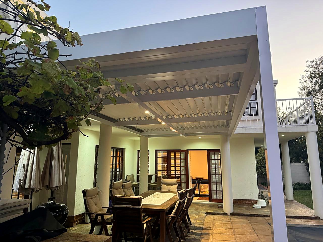 White louvre roof with glowing downlights over a Benoni patio at dusk
