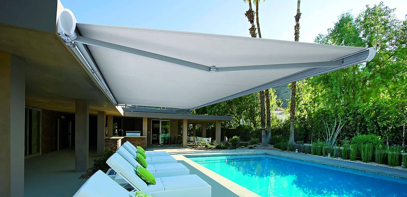 White fold-arm awning extended over a modern pool terrace