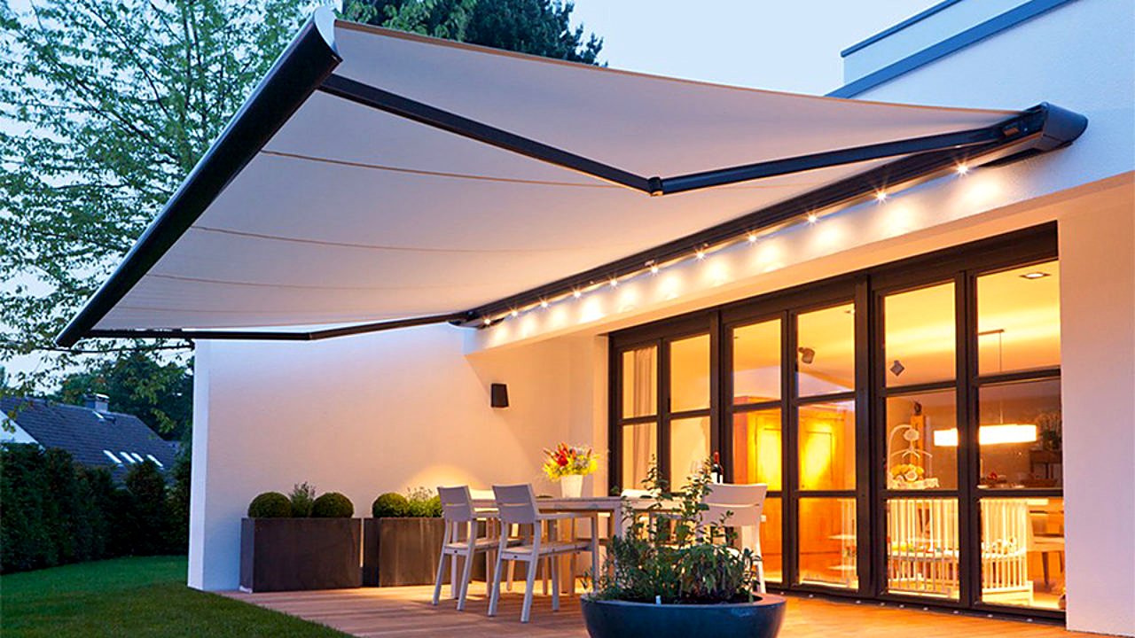 Retractable fold-arm awning with LED lighting over an evening patio
