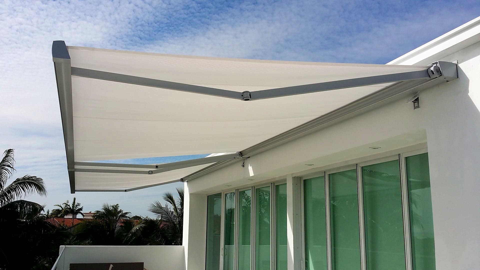 Two white fold-arm awnings extended from a modern villa balcony