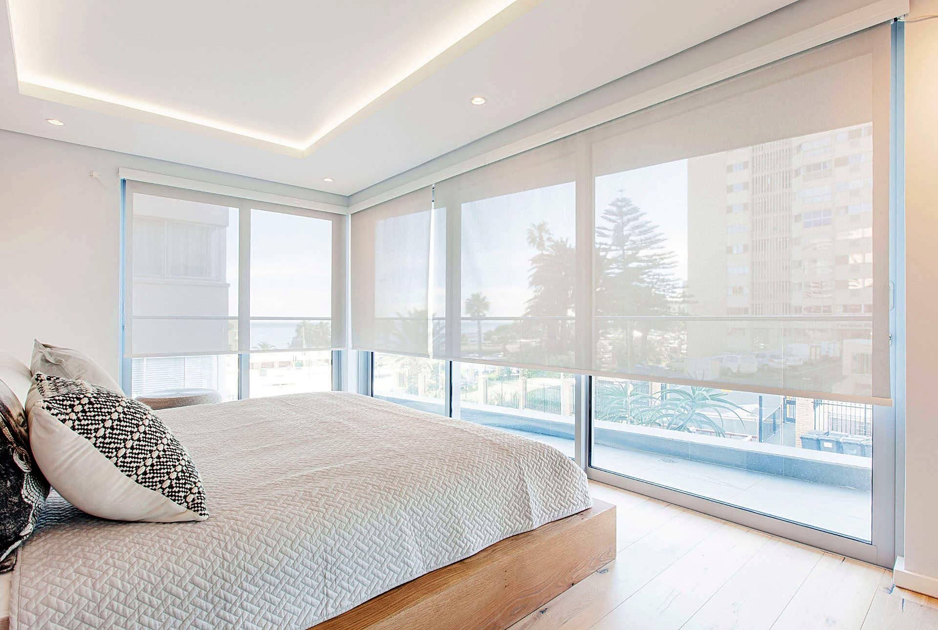 Sheer light-filtering roller blinds in a bright coastal bedroom