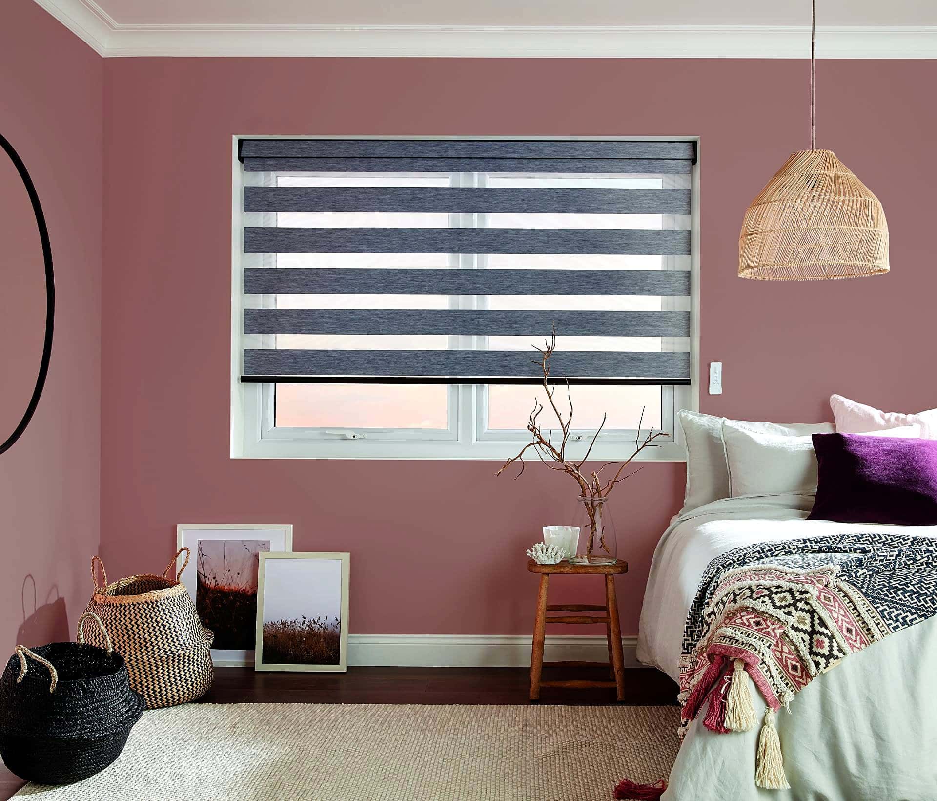 Grey zebra roller blind half open in a bedroom with a blush pink wall