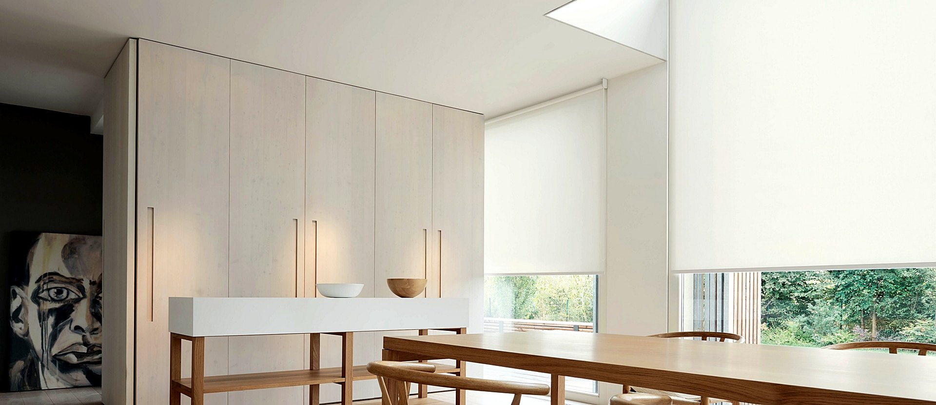 White roller blinds across the windows of a Scandinavian-style dining room