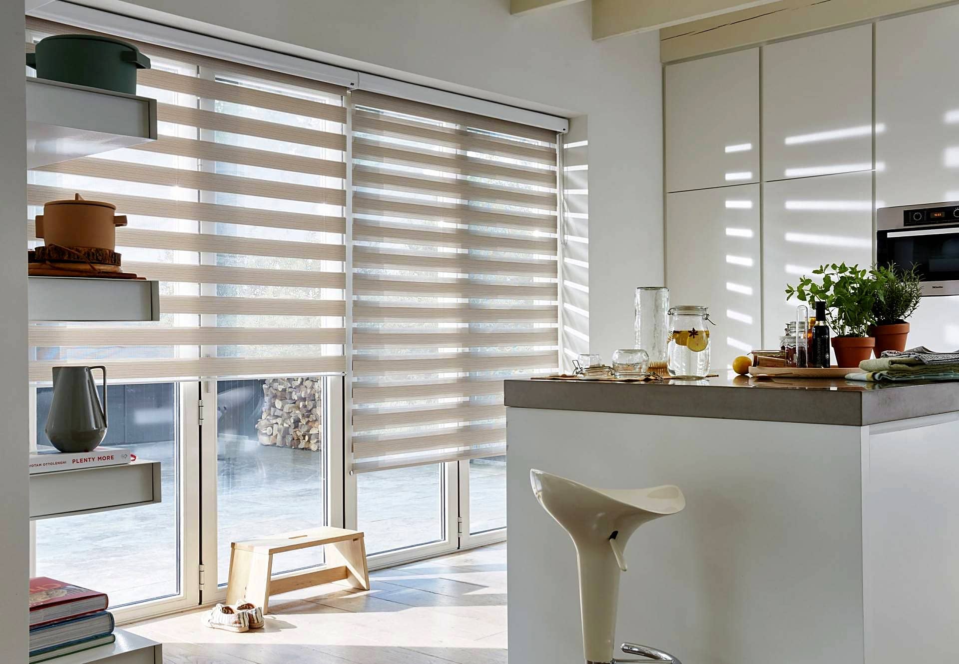 Beige zebra roller blinds filtering sunlight into a modern kitchen