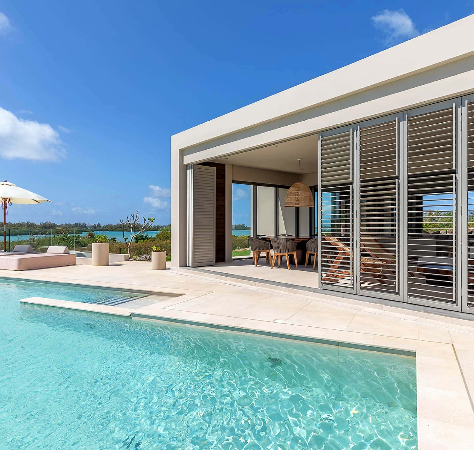 White aluminium shutters along the pool elevation of a modern villa