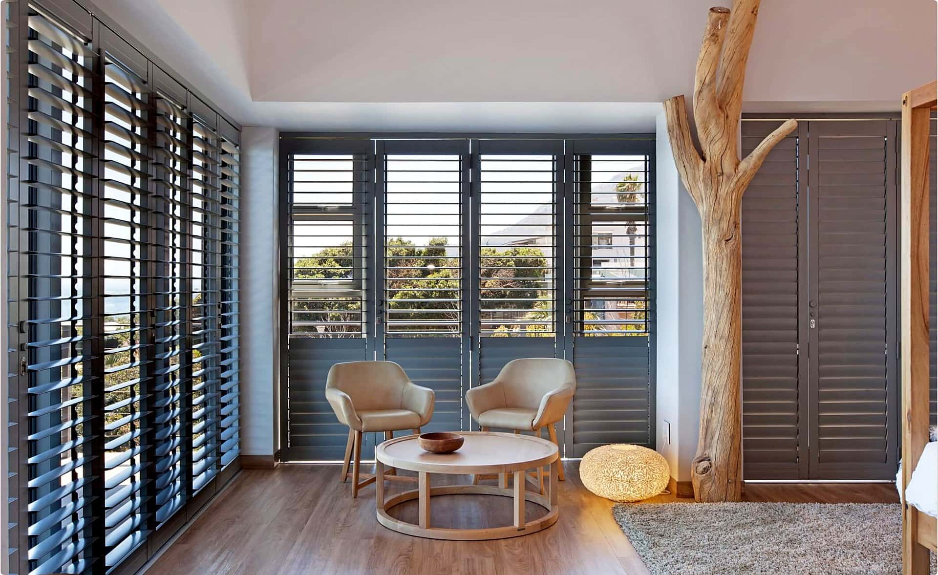 Wall of charcoal louvred shutters in a styled lounge