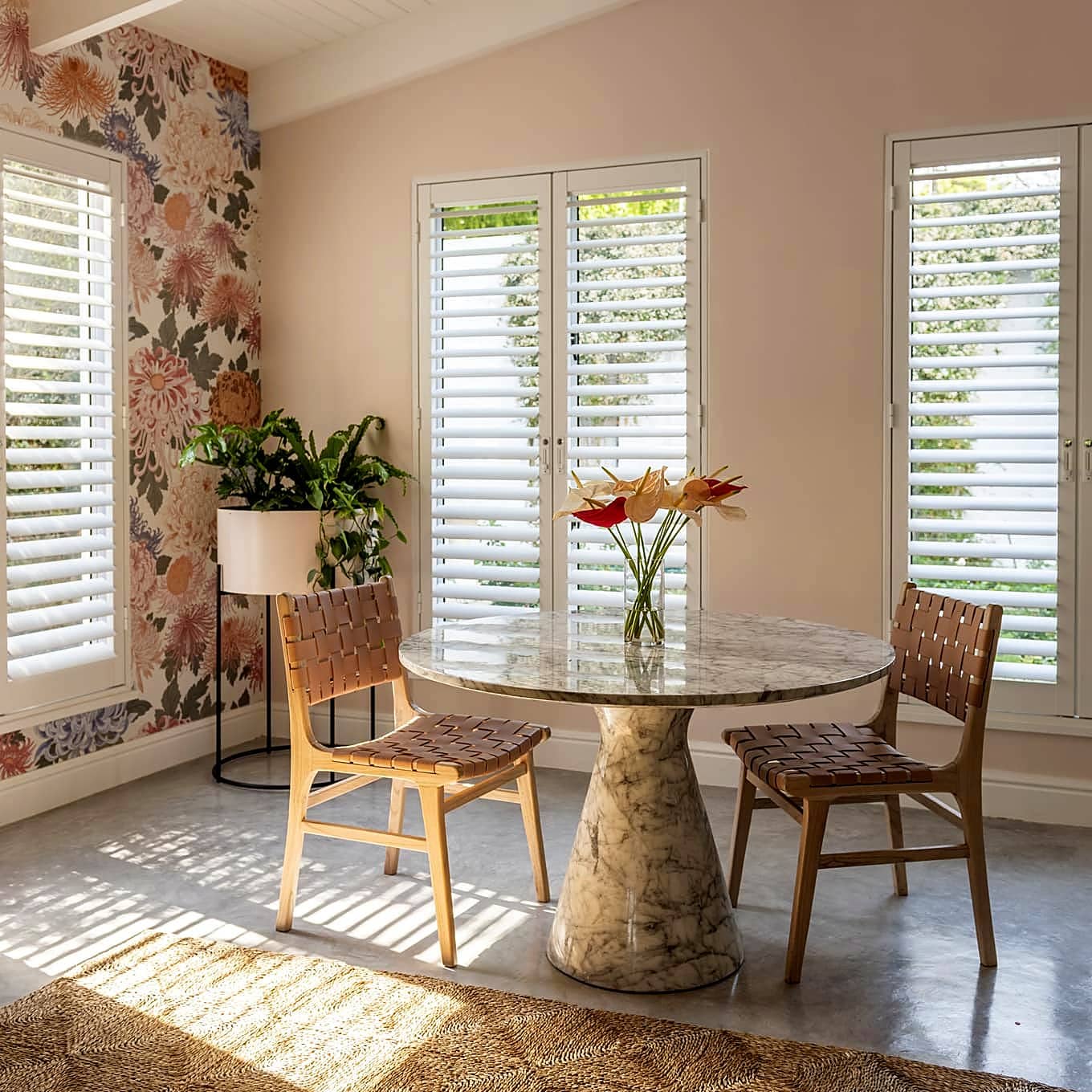 White shutters on three windows around a sunlit dining nook