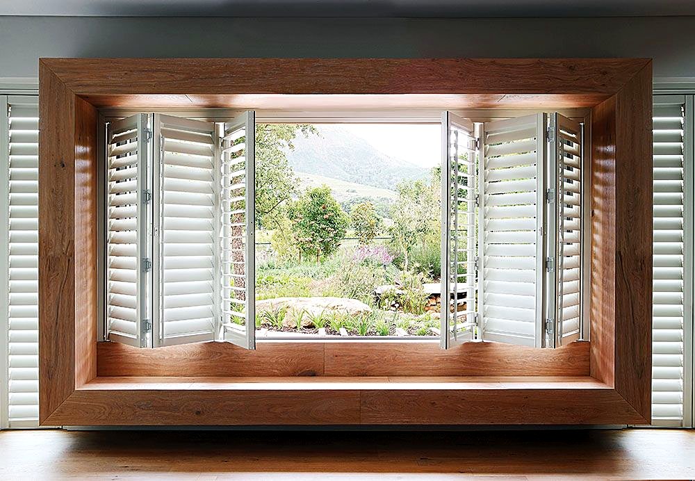 White bi-fold shutters around a timber window seat