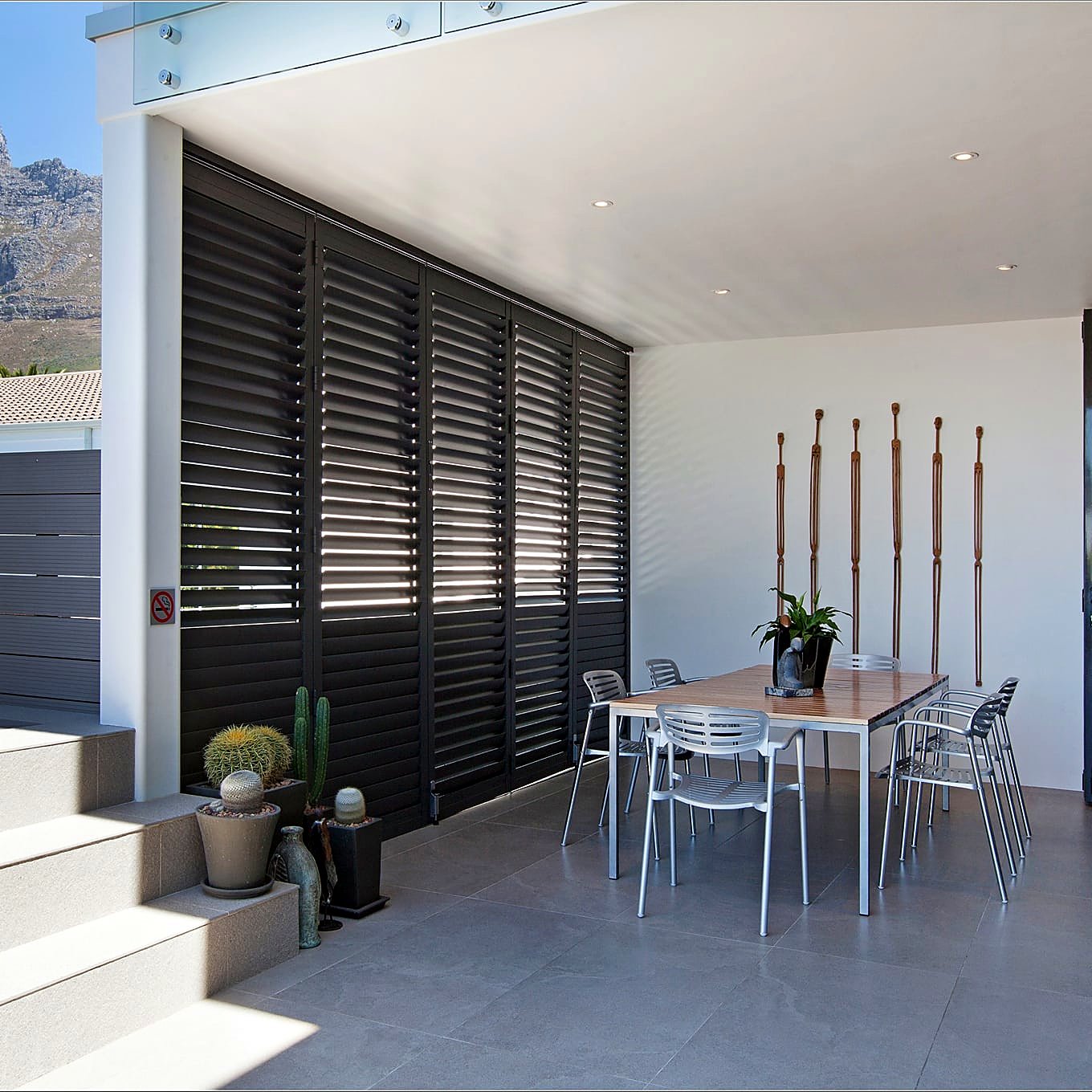 Black aluminium shutters on an outdoor terrace with Table Mountain behind