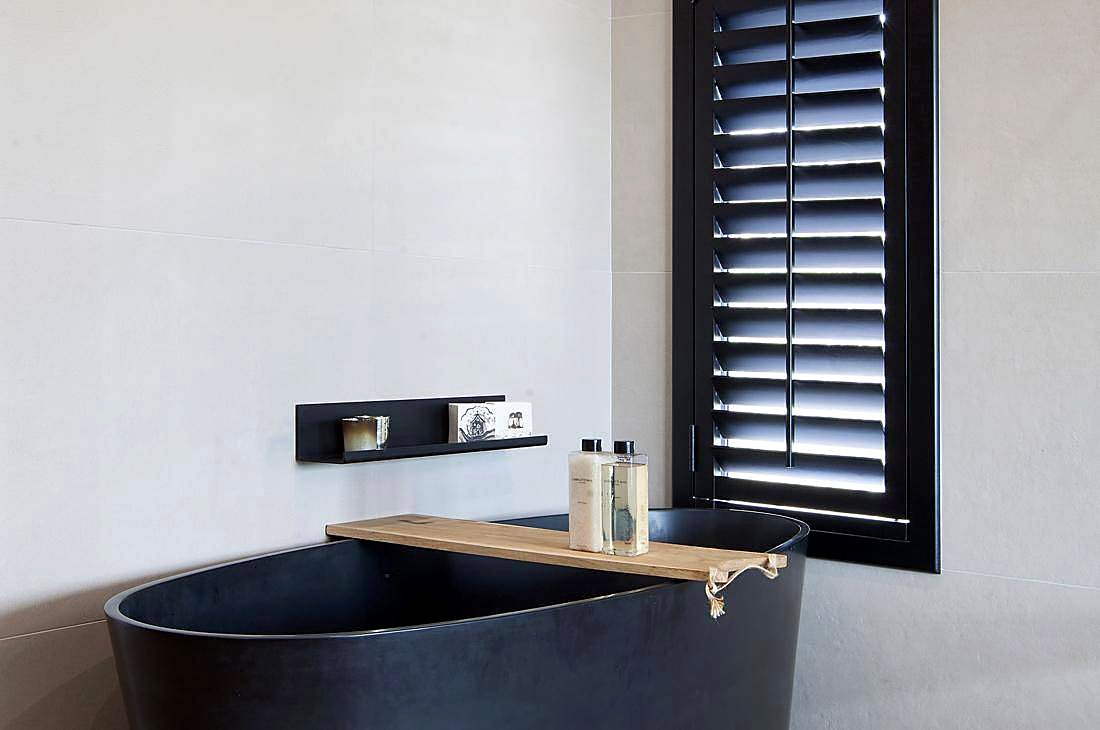 Black timber shutters above a freestanding bath