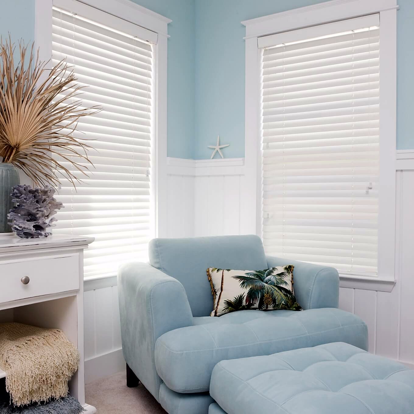 White faux-wood venetian blinds in a bright coastal lounge