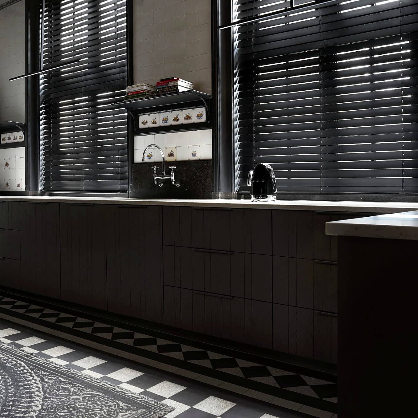 Black wood venetian blinds in a dark designer kitchen with patterned tiles